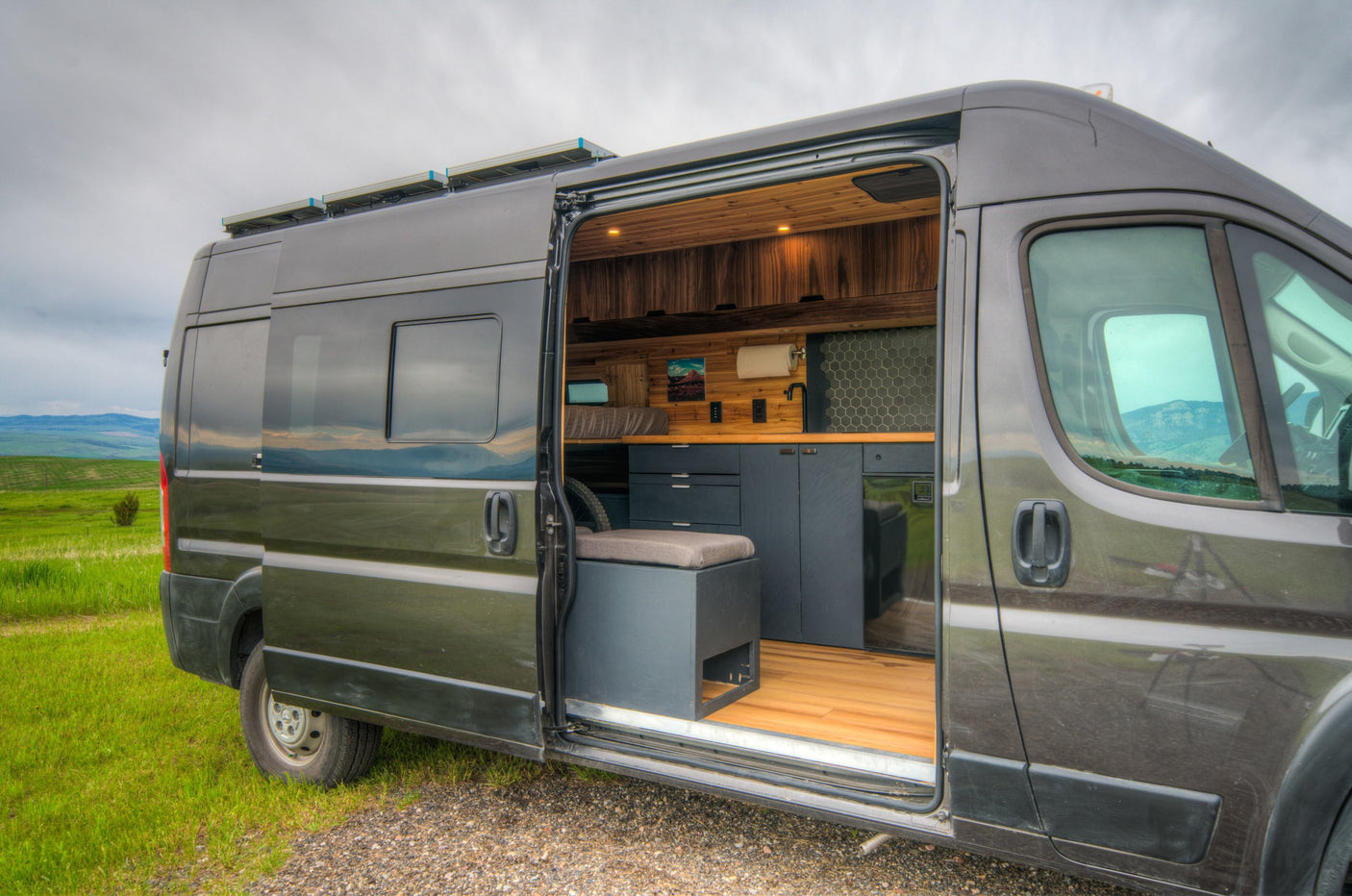 This RV rental offers a grey camper van with an open door revealing a modern interior