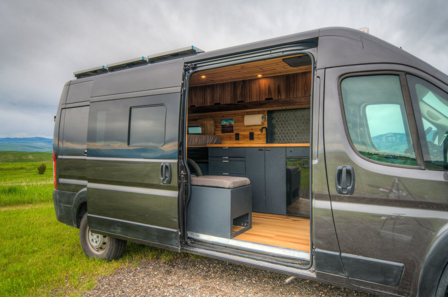 This RV rental offers a grey camper van with an open door revealing a modern interior