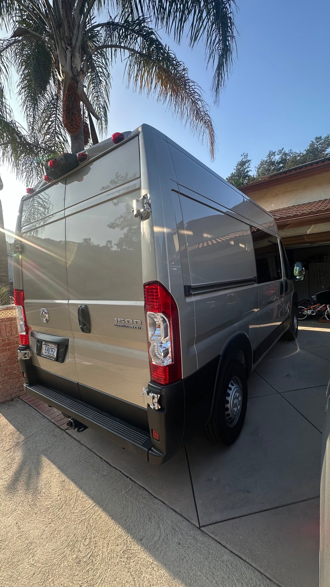 Gray Ram ProMaster camper van, available for RV rental, parked on a sunny driveway.