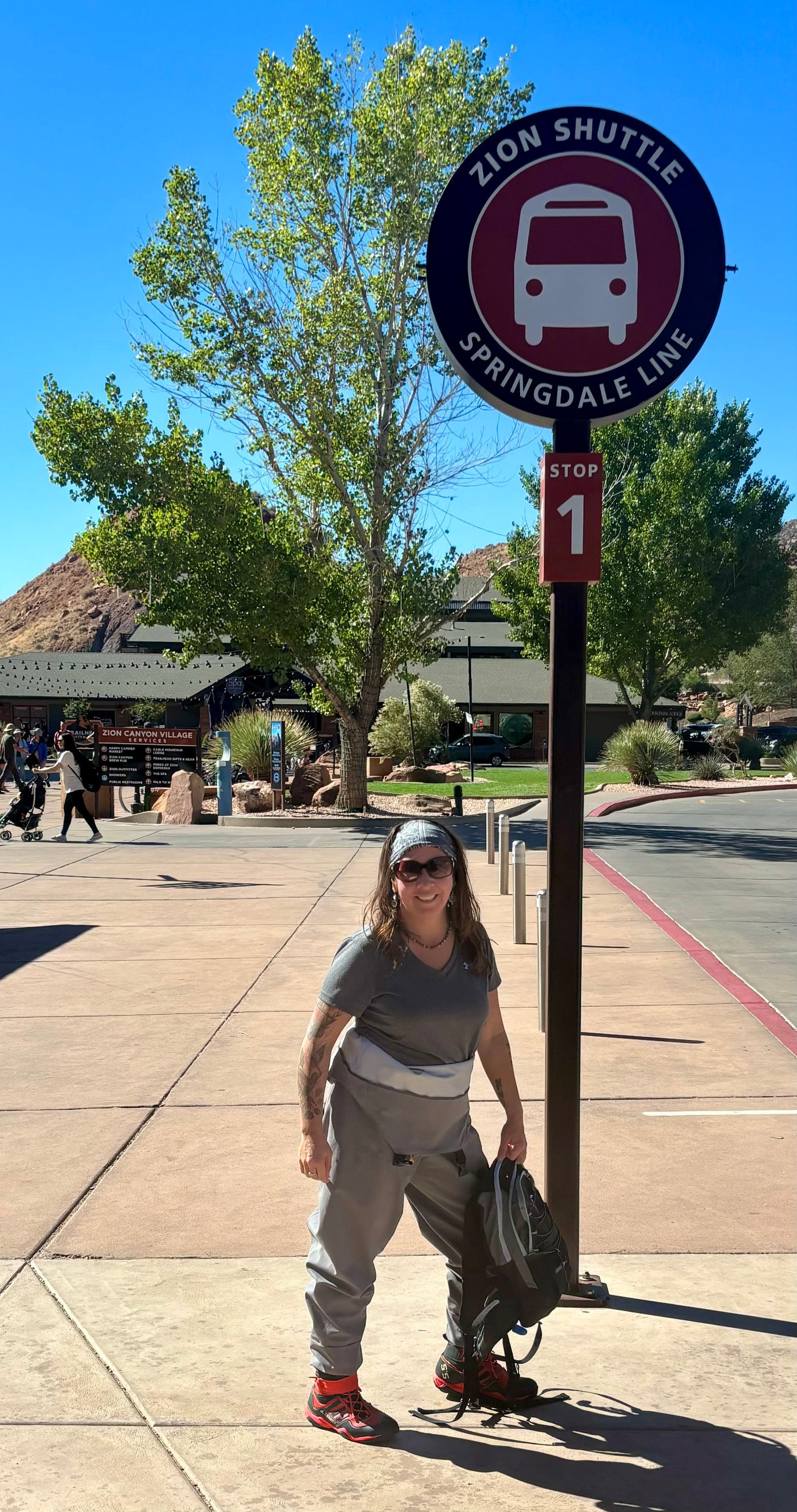 A woman at Zion's Springdale Line Shuttle Stop 1. Park your RV rental nearby and explore Zion by shuttle!