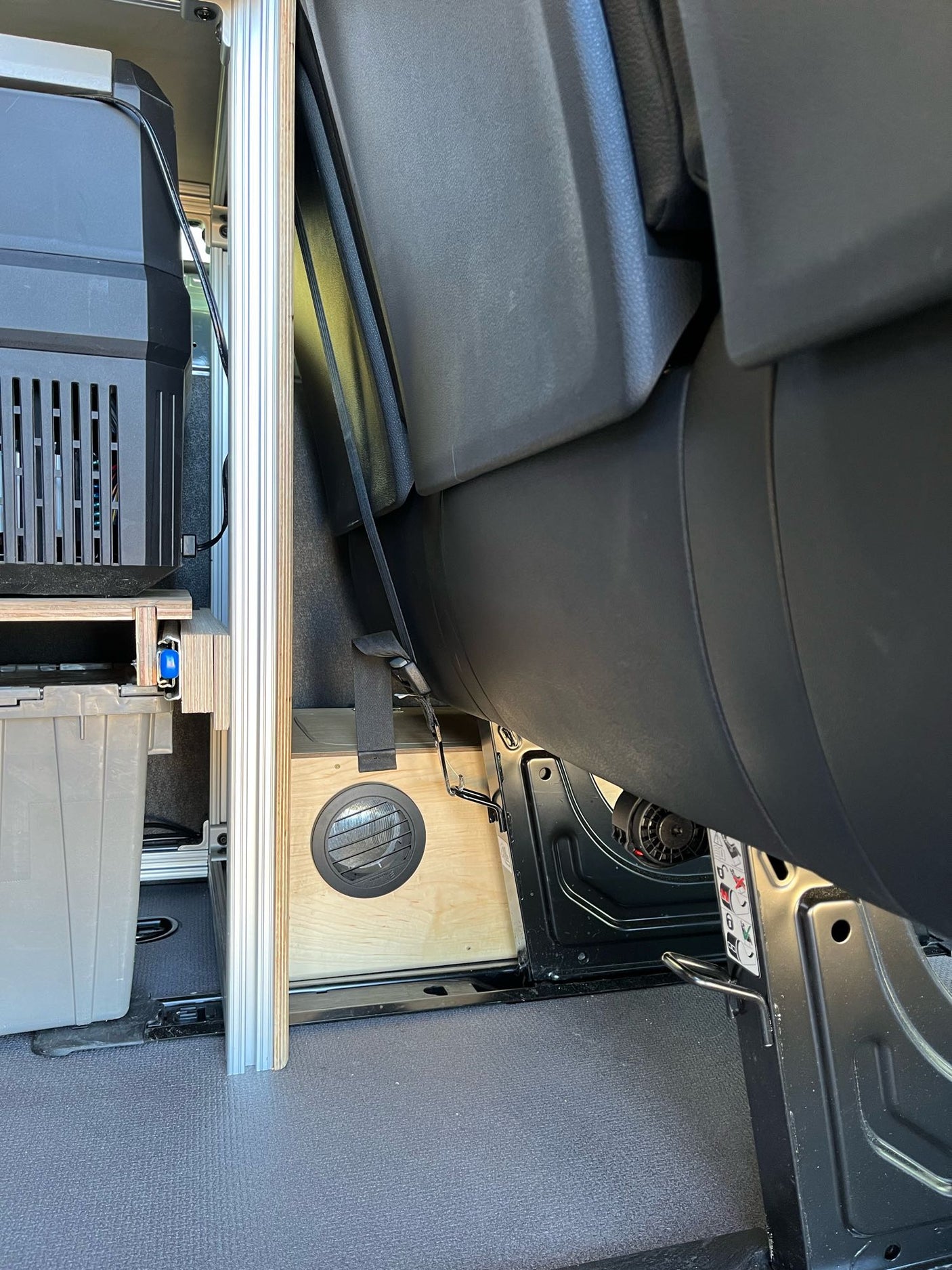 RV rental interior: portable fridge, custom camper van build with an air vent, and passenger seat.