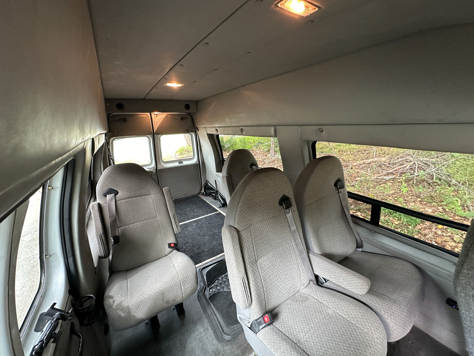 parked on a residential street.|White Ford RV rental parked roadside. Raised roof camper van