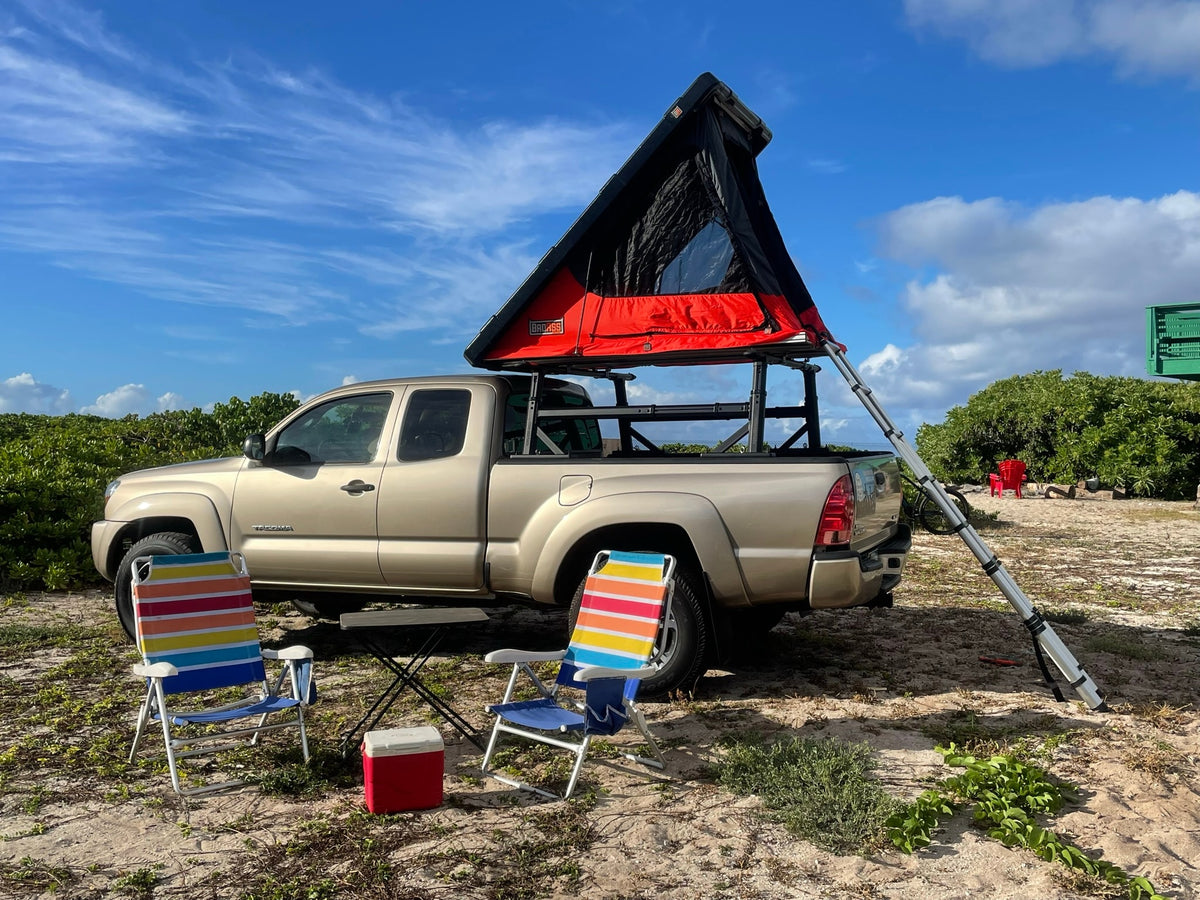 Explore with this RV-style rental setup: a tan truck with a deployed red & black rooftop tent, ladder, and colorful beach chairs. — photo 7