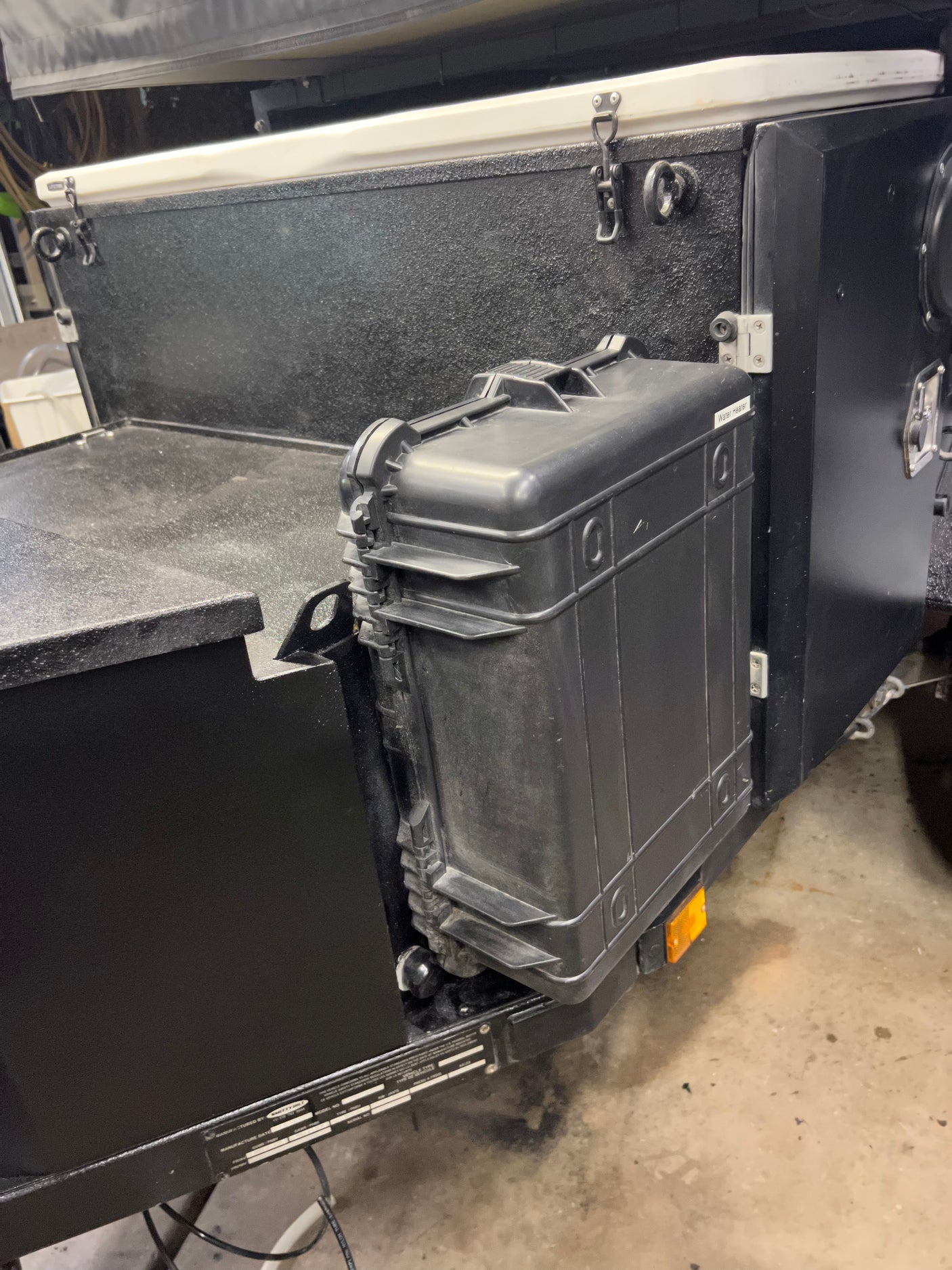 Close-up of a "Water Heater" case mounted on a rugged black RV rental. Practical outdoor gear storage.