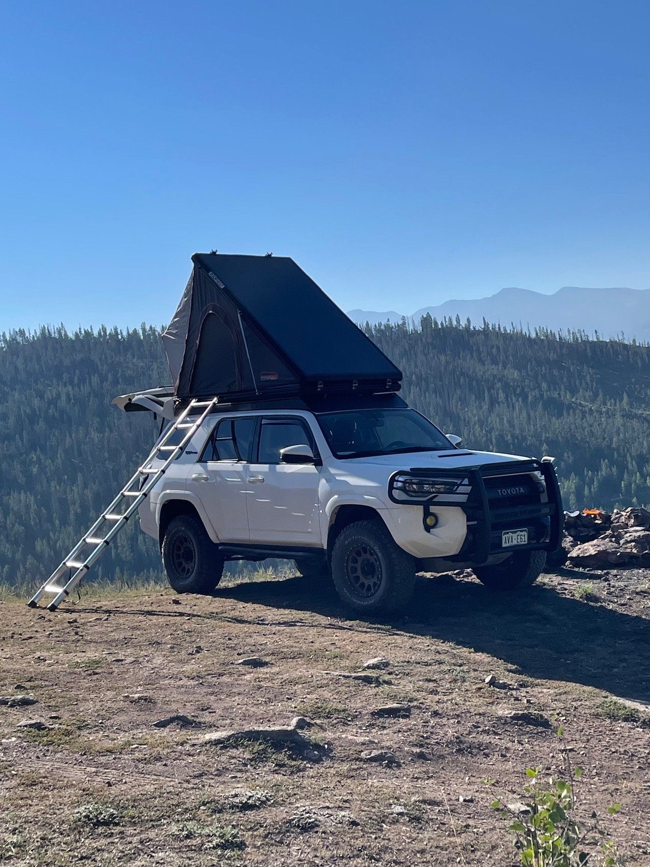 White Toyota 4Runner with rooftop tent and ladder deployed for off-grid camping. An ideal RV rental for mountain adventures. — photo 4