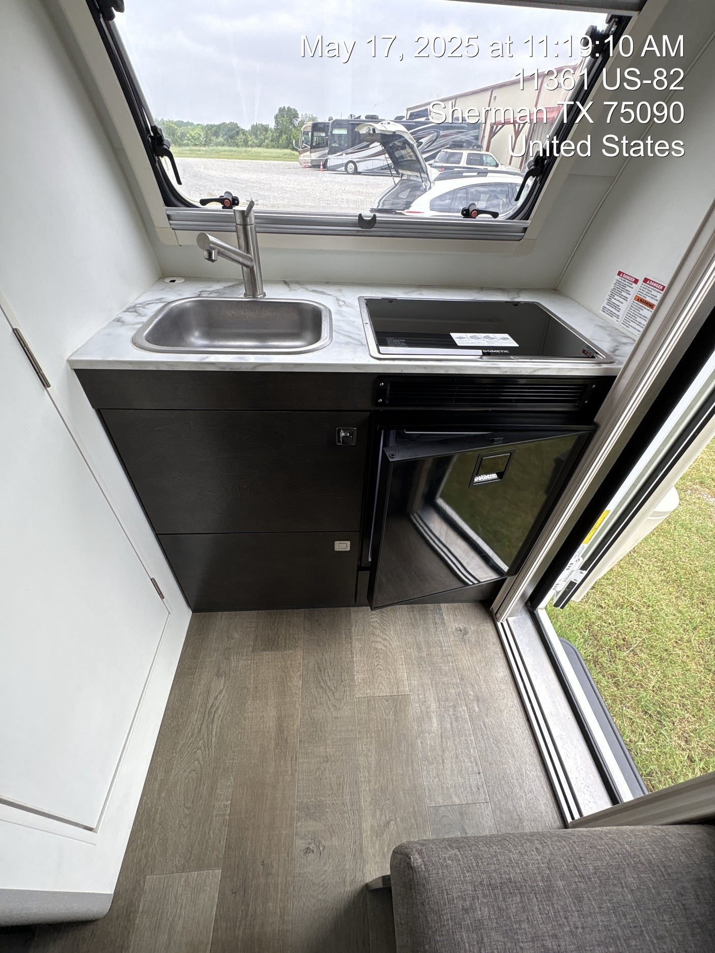 Inside an RV rental: a modern, compact kitchen with a sink, Dometic cooktop, and Isotherm fridge.