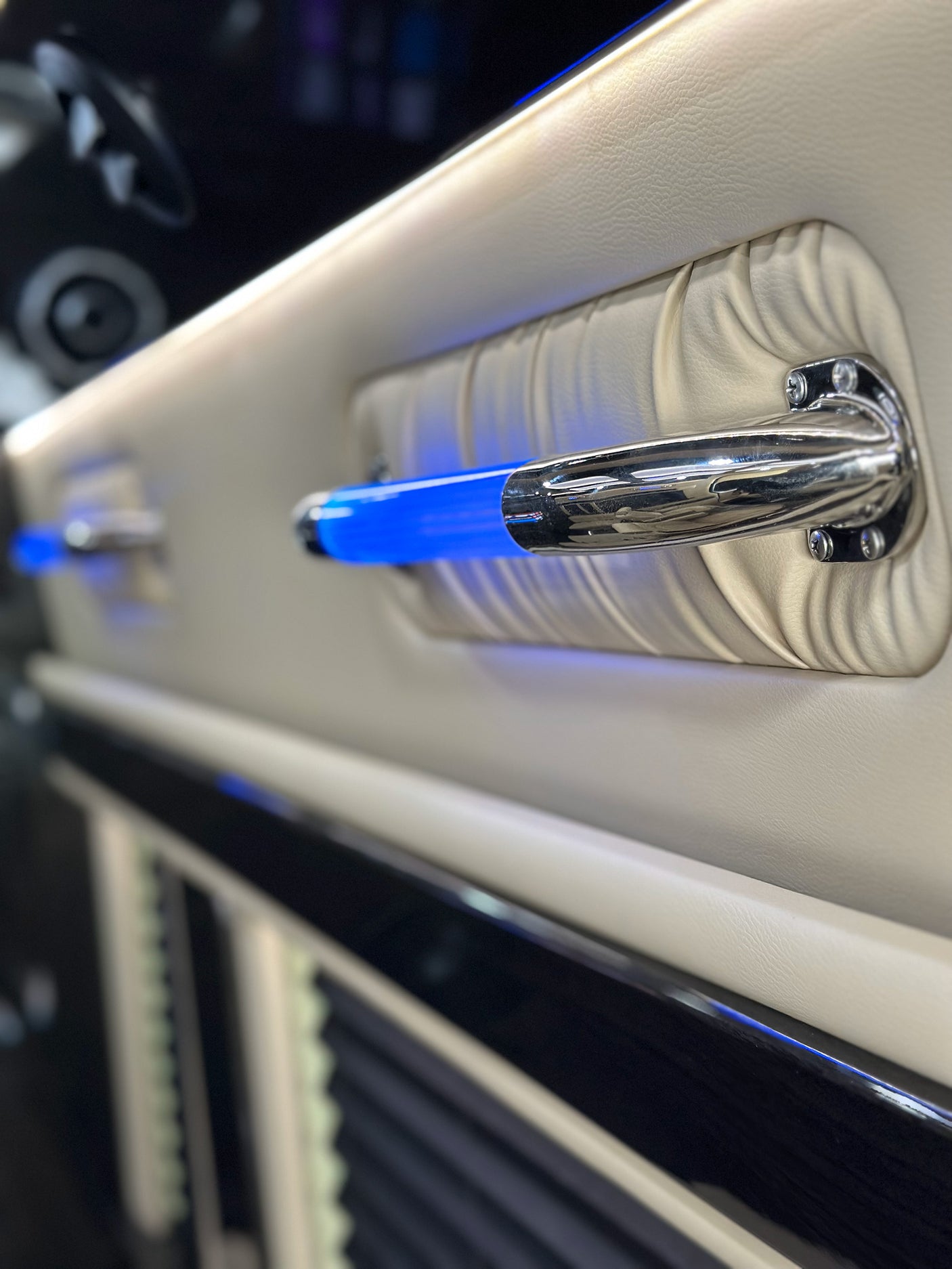 An RV rental's premium interior: illuminated blue grab handles, set against soft beige leather side paneling, emphasizing luxury details.
