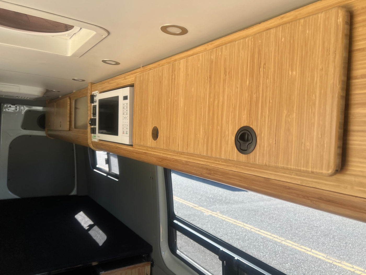 Inside an rv rental: custom bamboo cabinetry, integrated microwave, and ceiling vent for comfortable travel. — photo 13