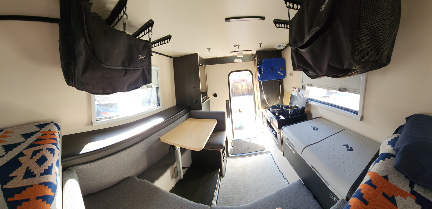 RV rental: Compact camper interior with kitchen, dining, and overhead storage for travel.