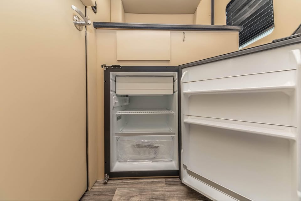 and elegant wood accents.|Luxurious RV rental interior with cream quilted beds