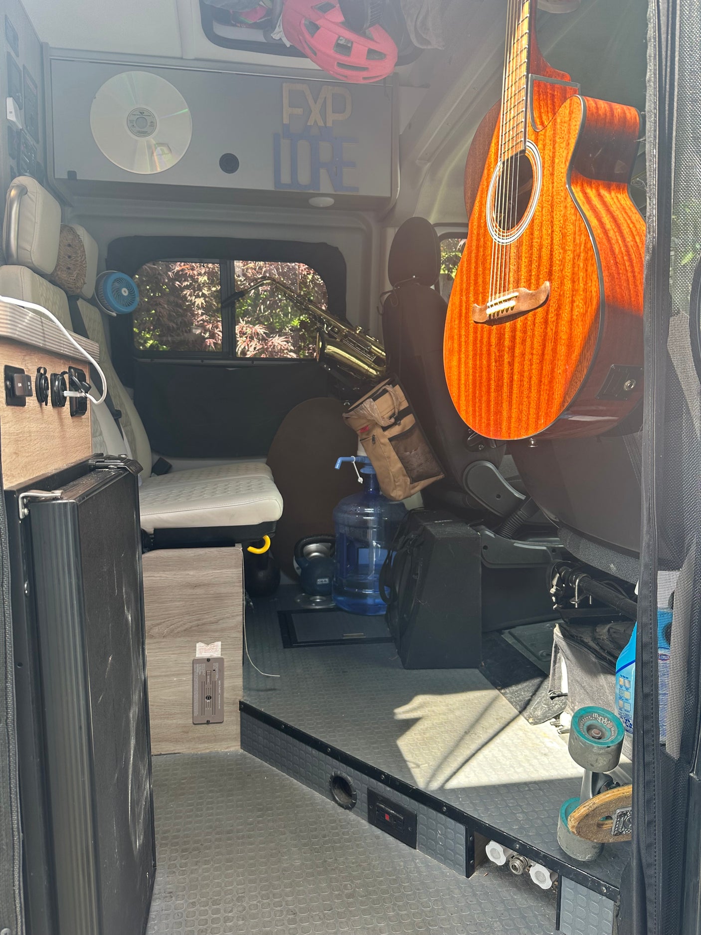 Inside an RV rental camper van: an acoustic guitar, saxophone, and adventure gear fill the custom-built interior.