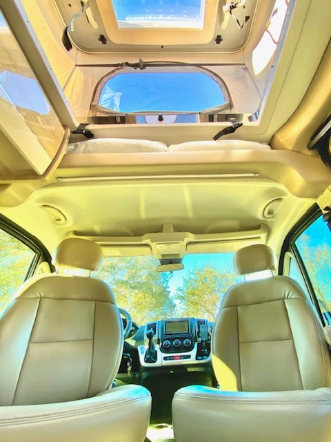and a cozy bed.|Bright RV rental interior with spacious living/dining