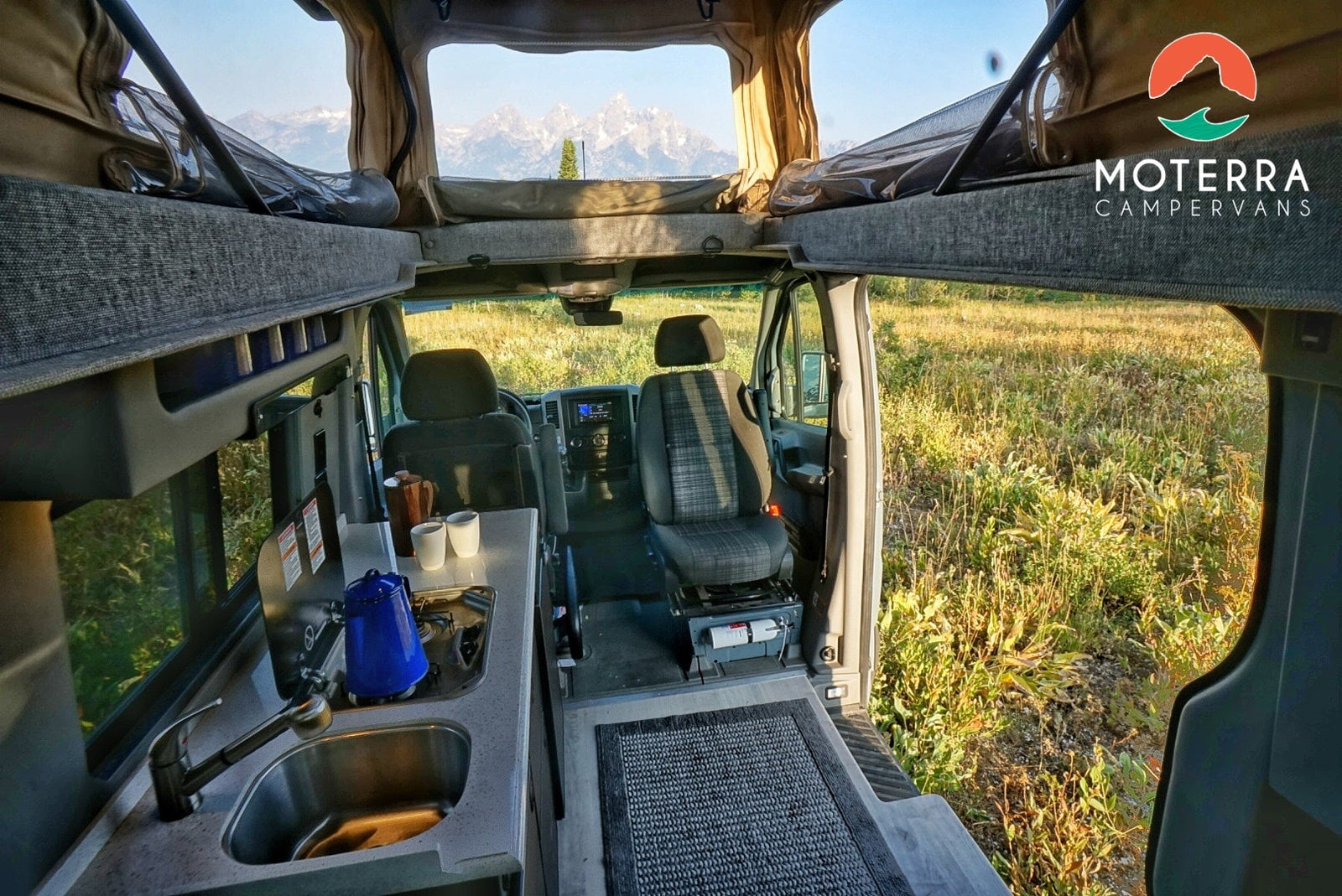 This RV rental offers a spacious interior: kitchen, swivel seats, pop-top bed, and majestic mountain views.