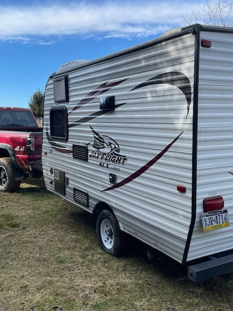 awning extended with two chairs on grass. Ideal for camping and outdoor adventure.|RV rental: Jayco travel trailer in a grassy field