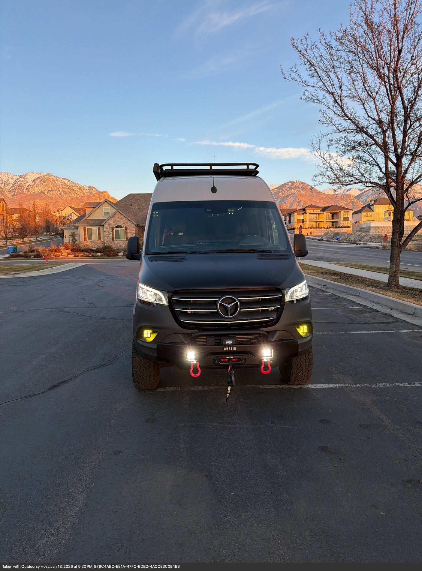 Get ready for adventure! This rugged Mercedes-Benz Sprinter rv rental, equipped with off-road gear, is parked with snowy mountain views at sunset.