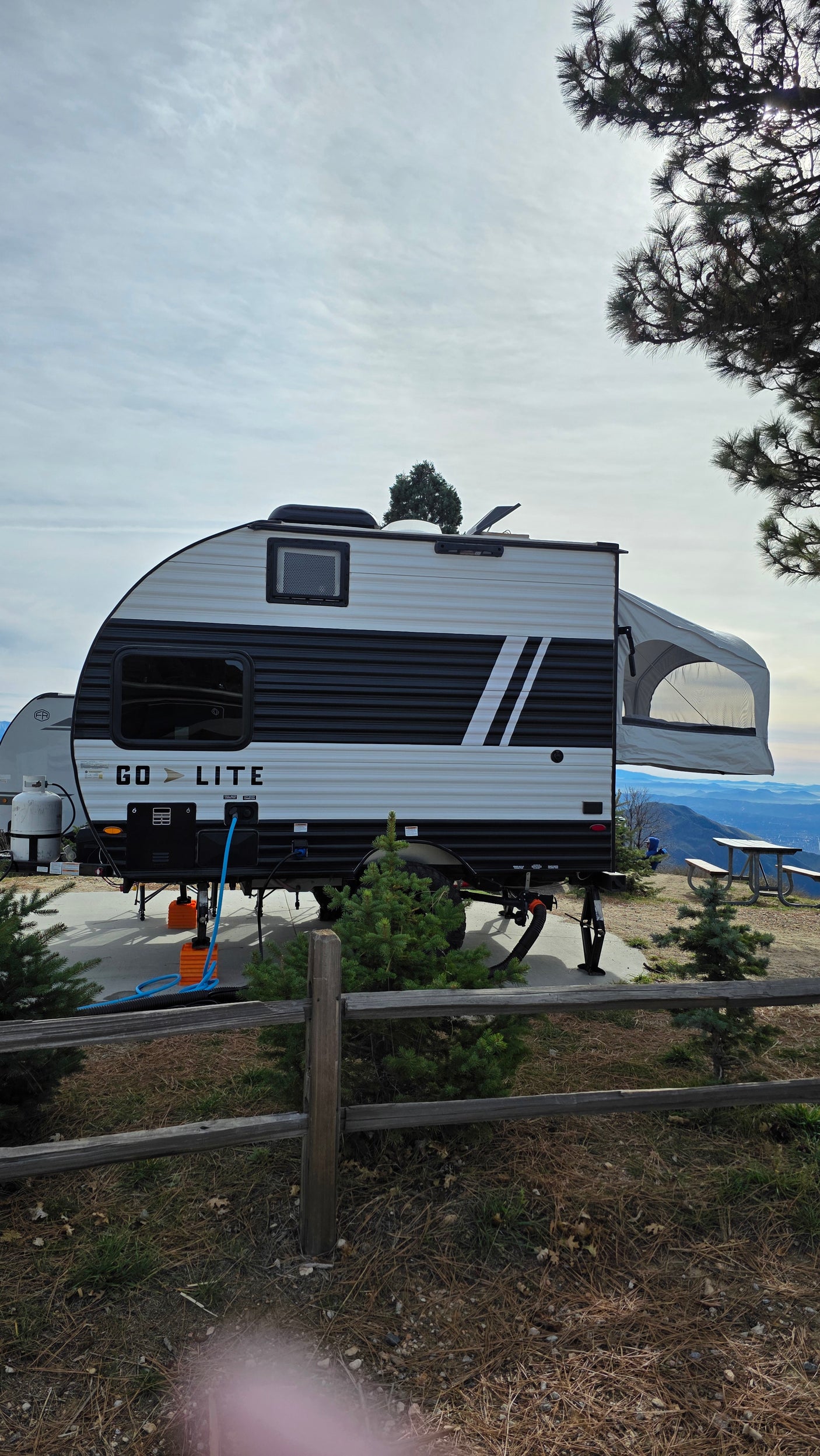 A Go Lite RV rental travel trailer at a mountain campsite, featuring a panoramic valley view and a rear pop-out.
