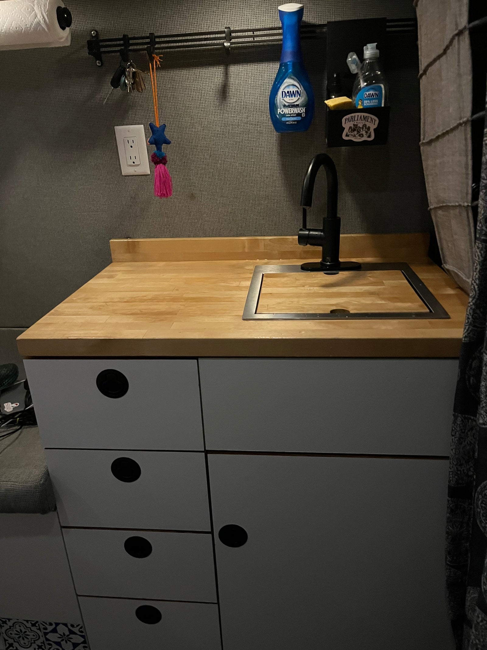 RV rental kitchen: compact sink, wood counter, and storage with essentials like Dawn soap.
