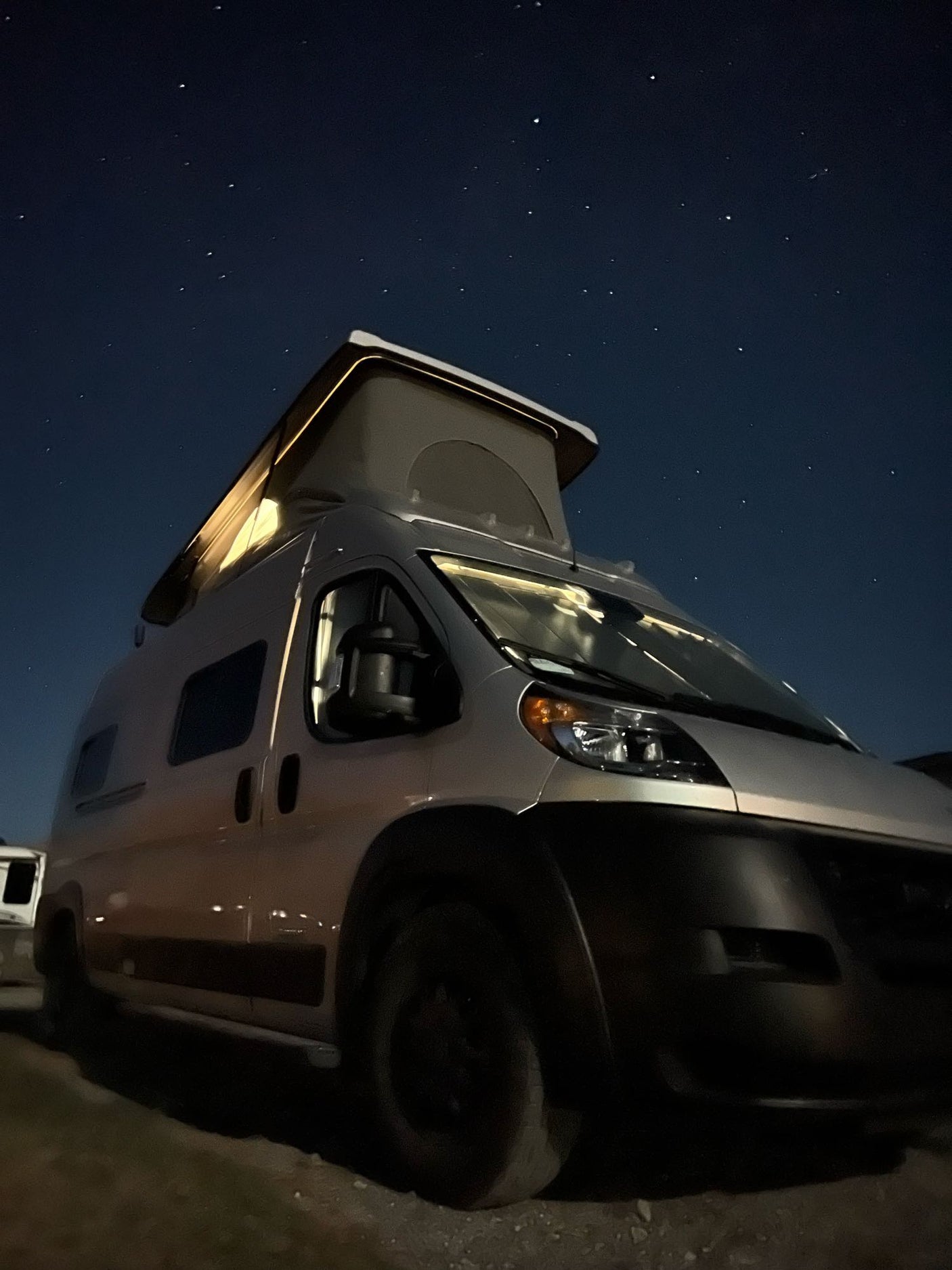 Starry night over an RV rental: a silver pop-top camper van, subtly lit. Ideal for remote camping adventures.