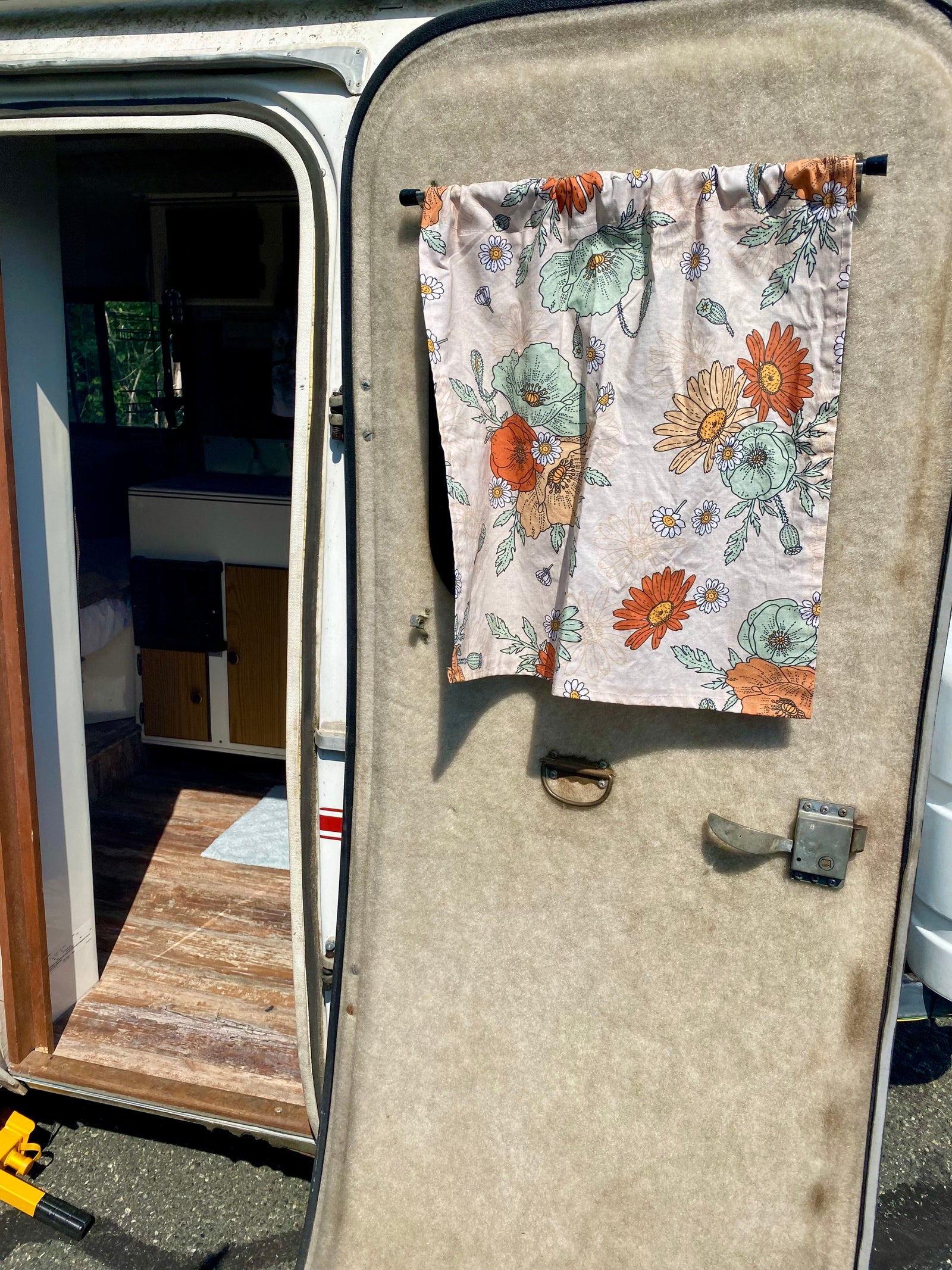 is hitched to a black pickup truck on an outdoor paved lot with trees.|Cozy RV rental interior with a compact kitchen
