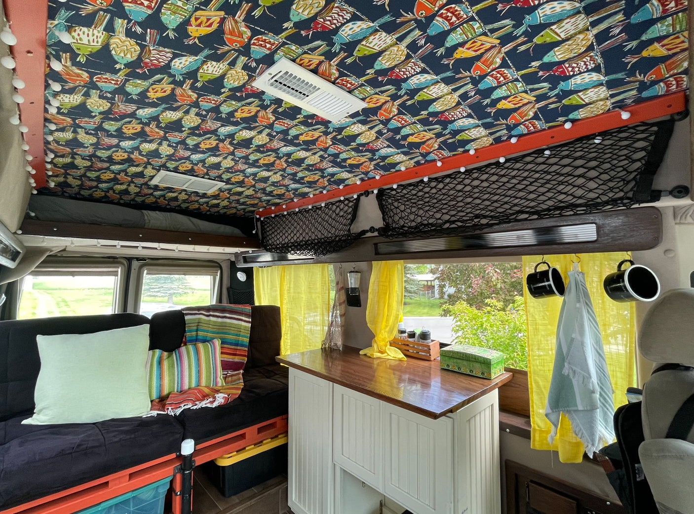 showcasing grand mountains under a blue sky. Perfect for outdoor adventures.|An RV rental silver van awaits adventure at a tranquil forest campsite with a lake in the background.|Cozy camper van interior for rv rental