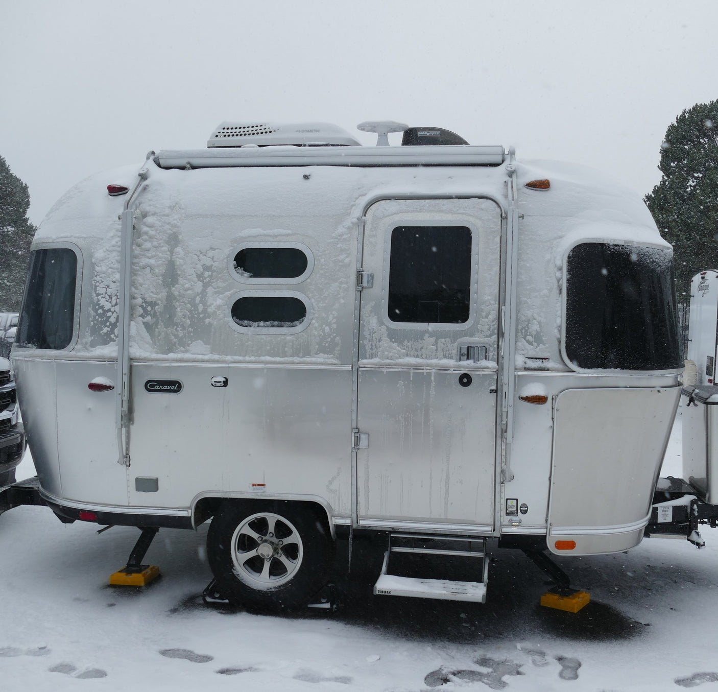 Snow-covered silver Airstream travel trailer, ideal for a cozy winter rv rental getaway.