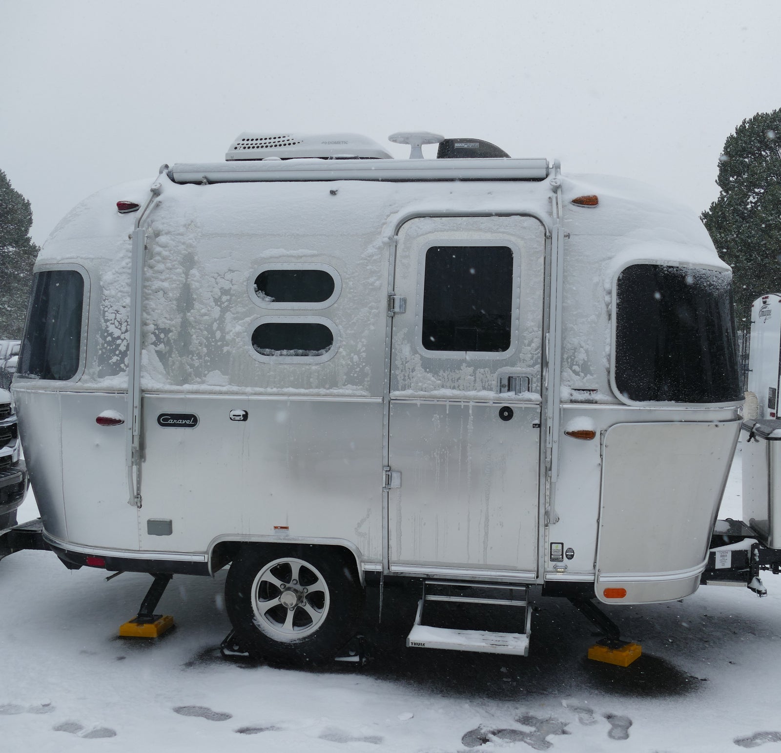 Snow-covered silver Airstream travel trailer, ideal for a cozy winter rv rental getaway.