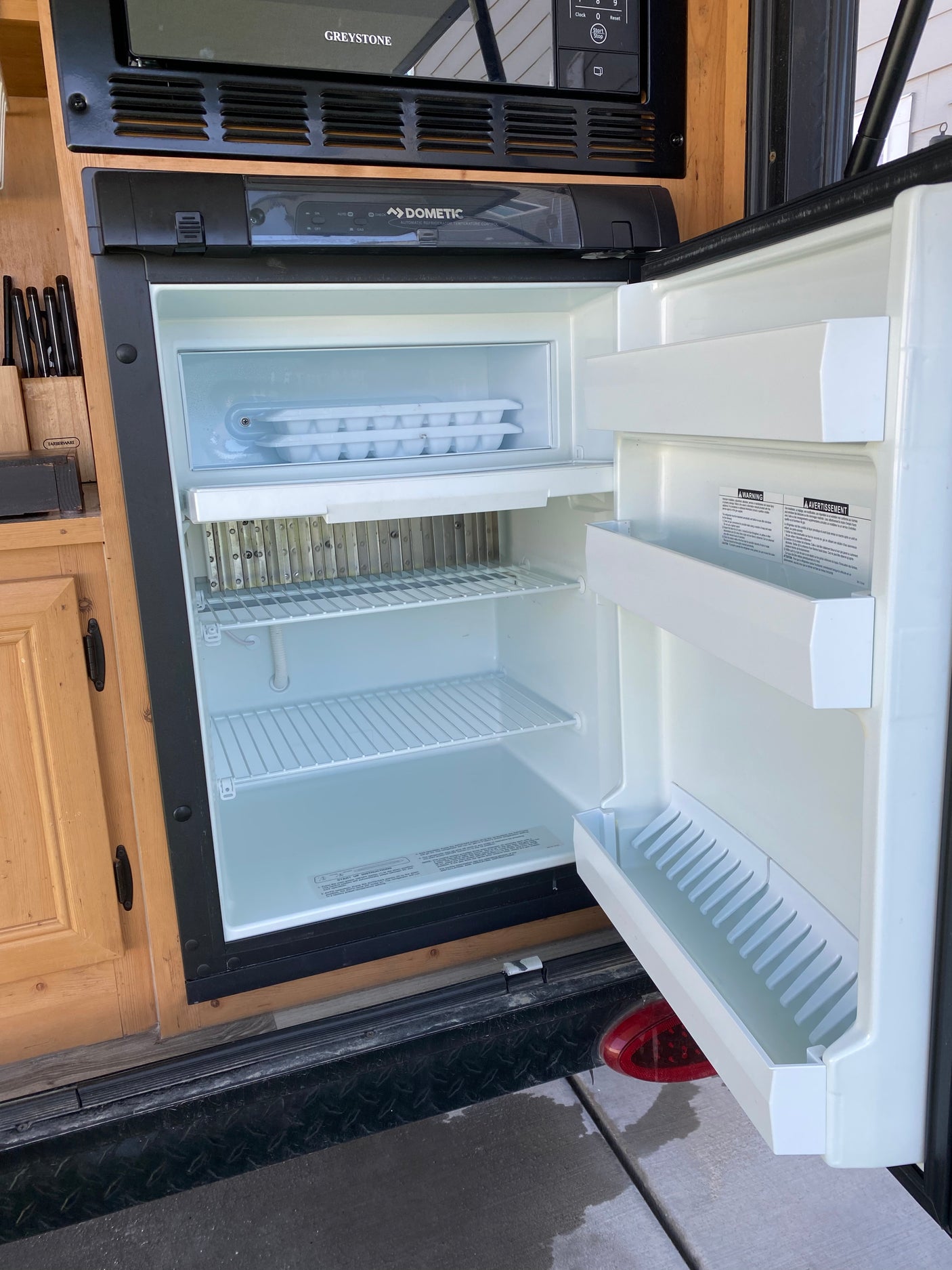 Clean, empty Dometic refrigerator in an RV rental. Freezer with ice trays, clear interior ready for use.