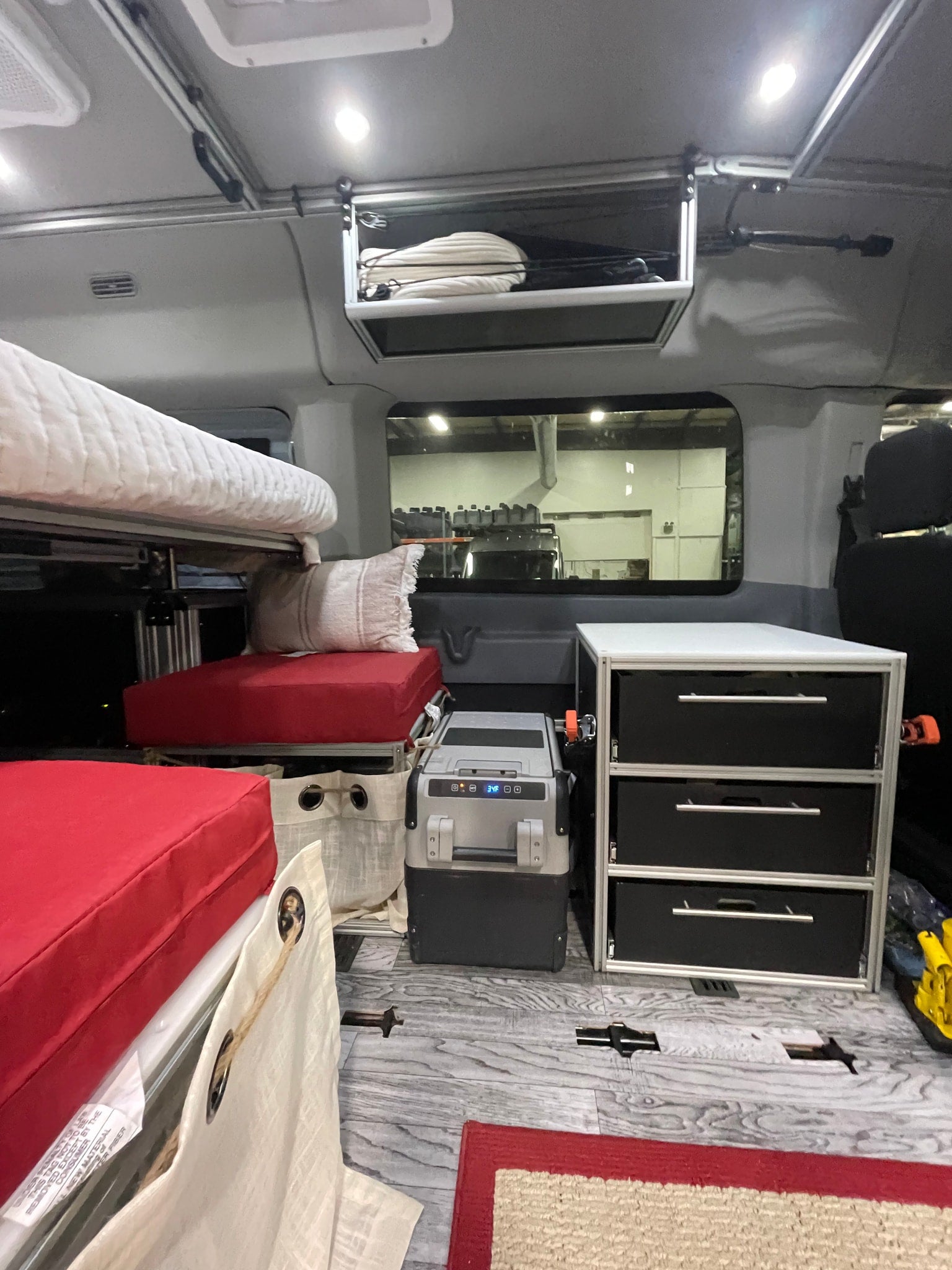 RV rental interior features bunk beds, a portable fridge displaying 34F, and ample storage drawers for a comfortable journey.