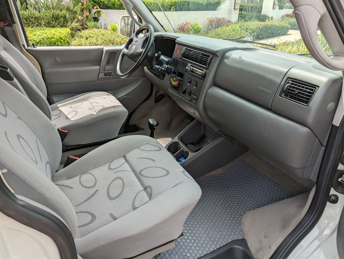 RV rental interior: spacious front cabin with gray seats, dashboard, and manual shifter.