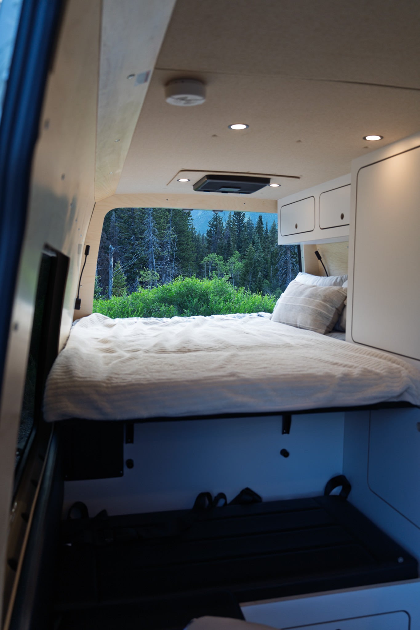Experience nature with an rv rental! This cozy camper van features a bed, cabinets, and a scenic forest view.