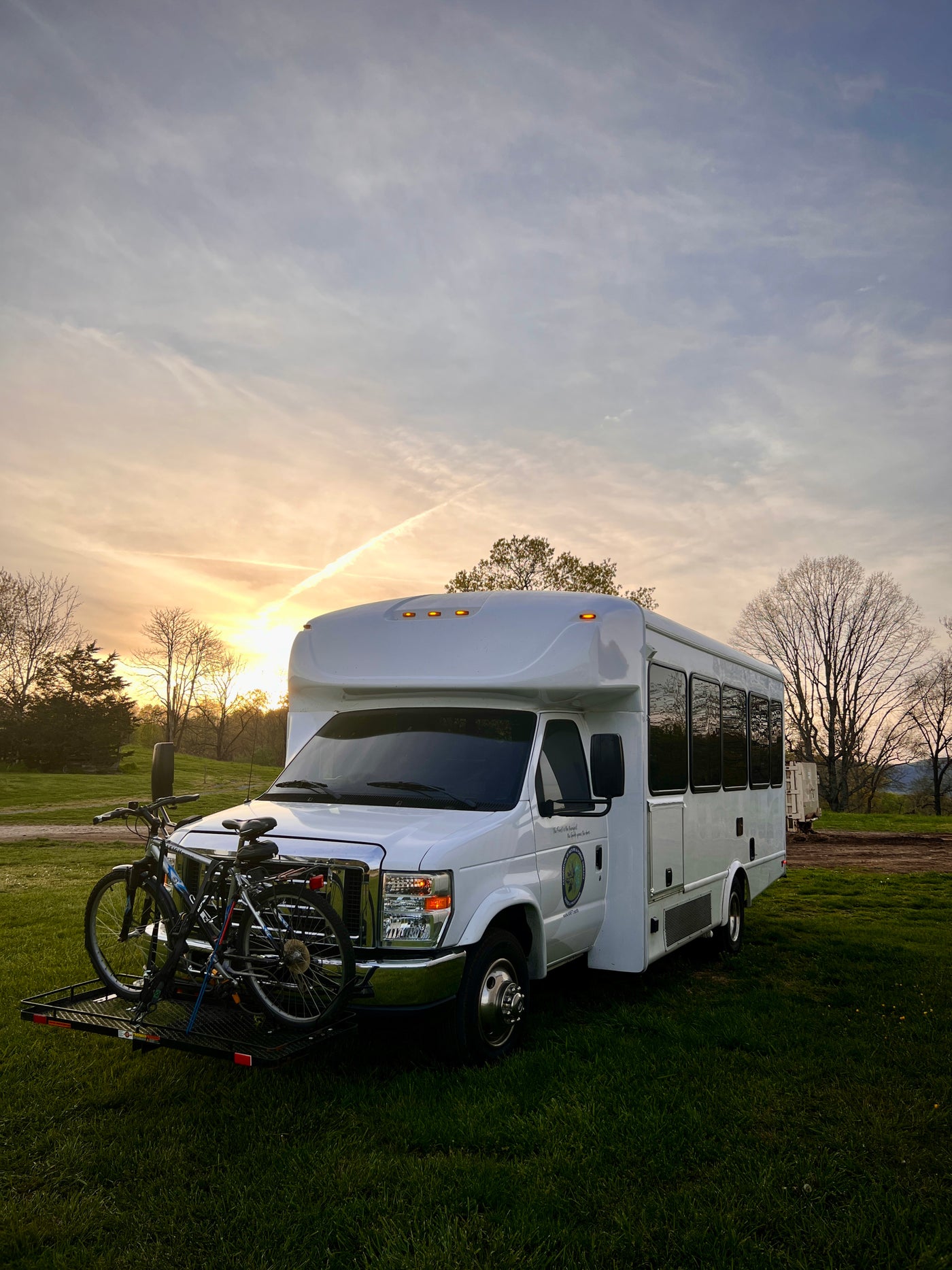 White RV rental with front-mounted bikes, parked on green grass at sunset. Ideal for outdoor adventures. — photo 20