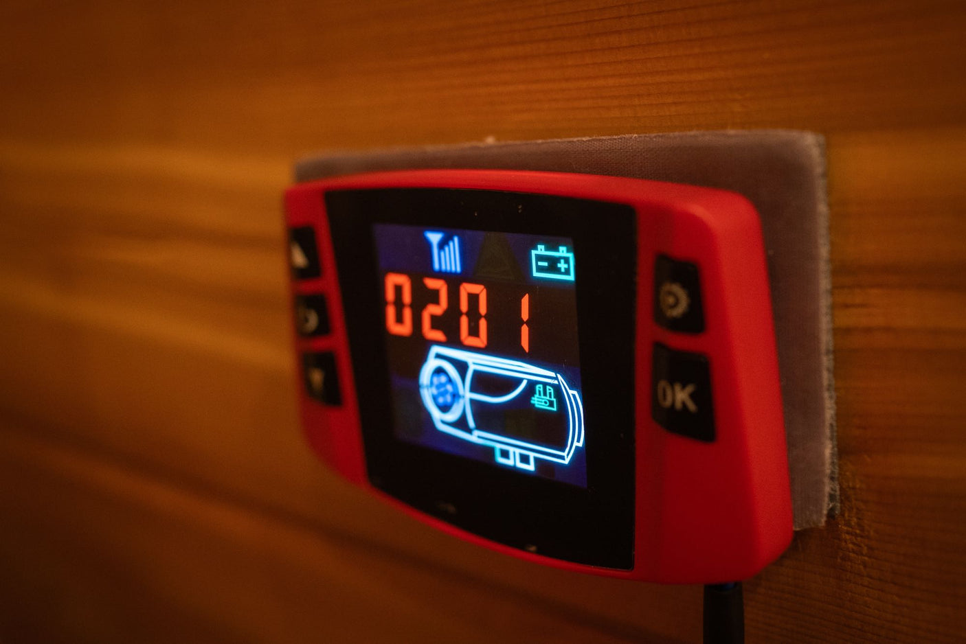RV rental's red heater control panel, showing 0201, signal, and battery on a wooden wall.