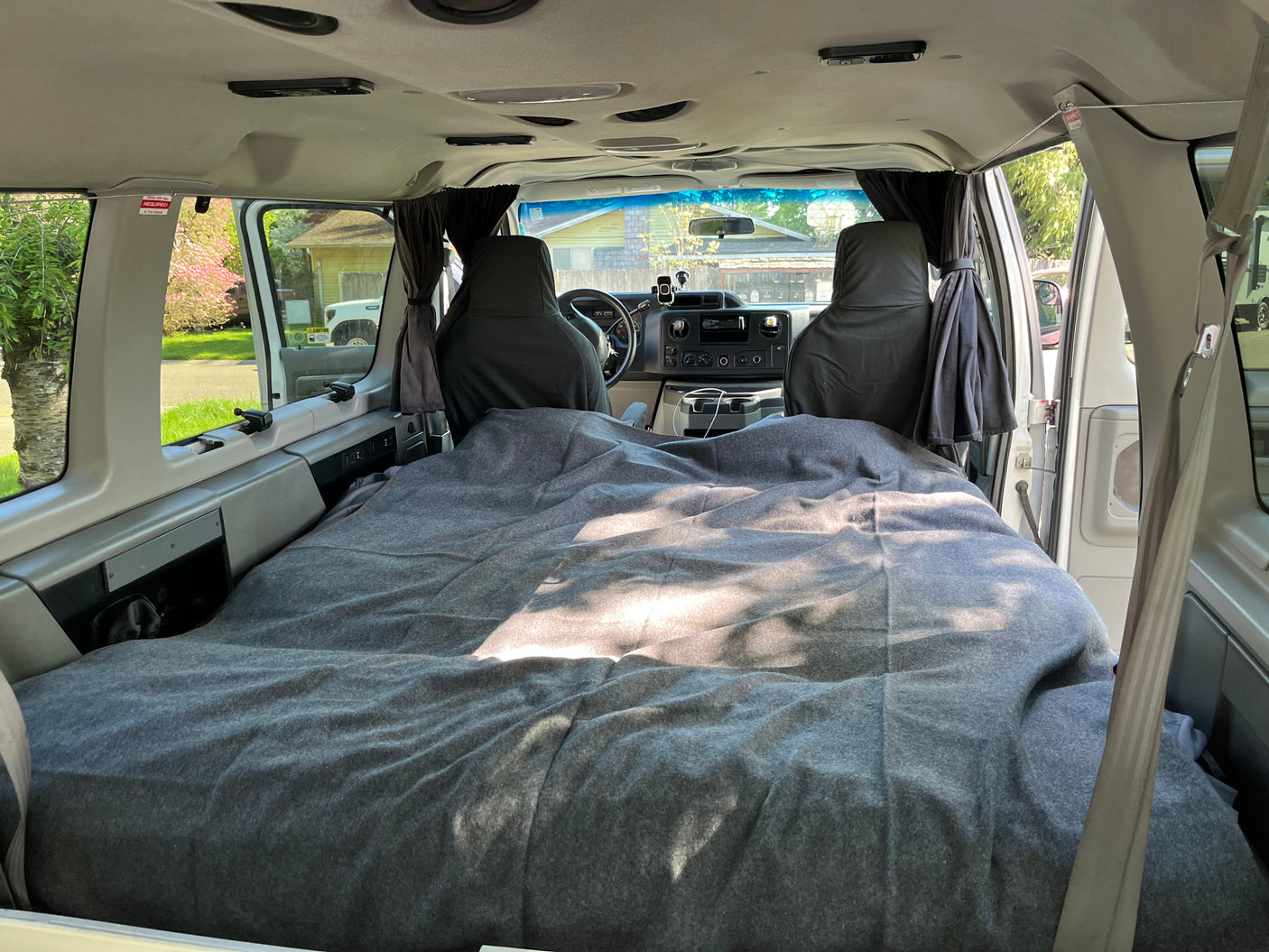 Cozy RV rental camper van interior: a made bed and front cockpit visible, ideal for custom travel adventures.