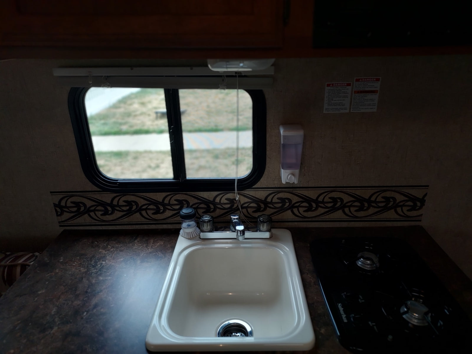 and a window with a pull-down shade.|Overhead view of an RV rental bathroom with a white shower base