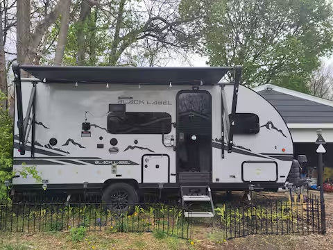 Stylish light gray rv rental travel trailer with an extended awning and mountain graphics