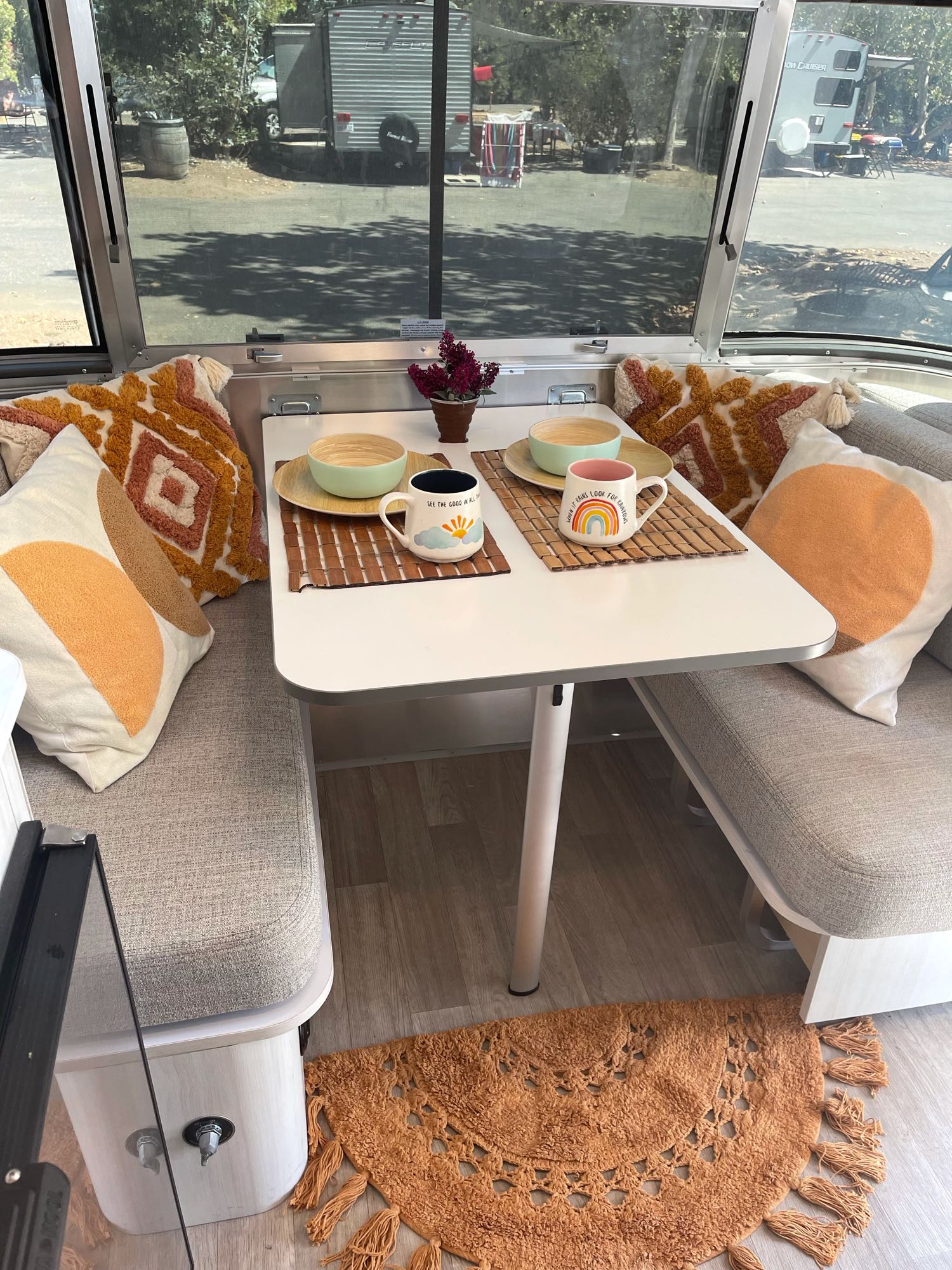 Cozy RV rental dinette with seating, set table, and outdoor views for your next camping adventure.