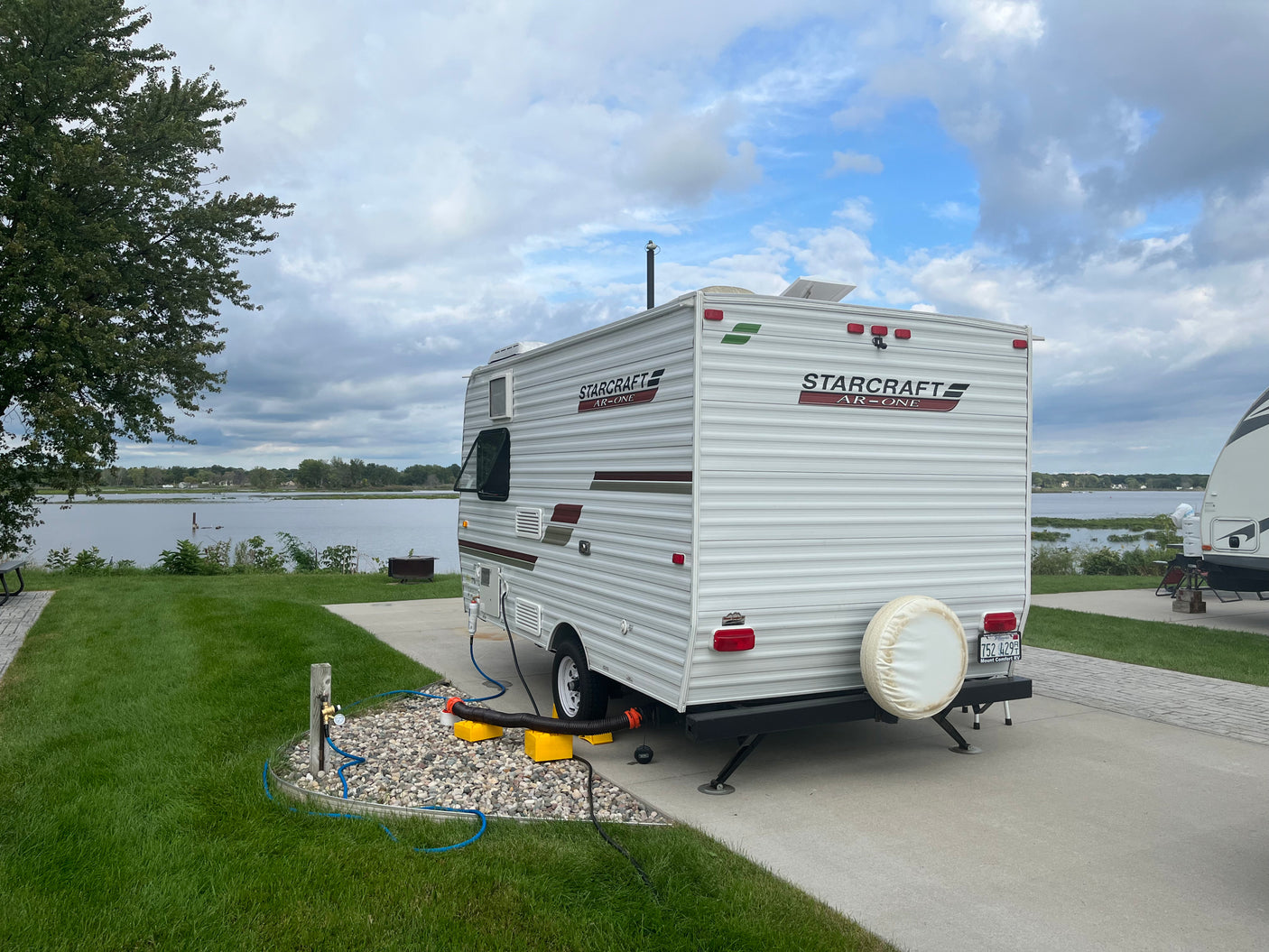 This rv rental is set up lakeside on a paved pad, complete with water, sewer, and power hookups, and a spare tire on back.