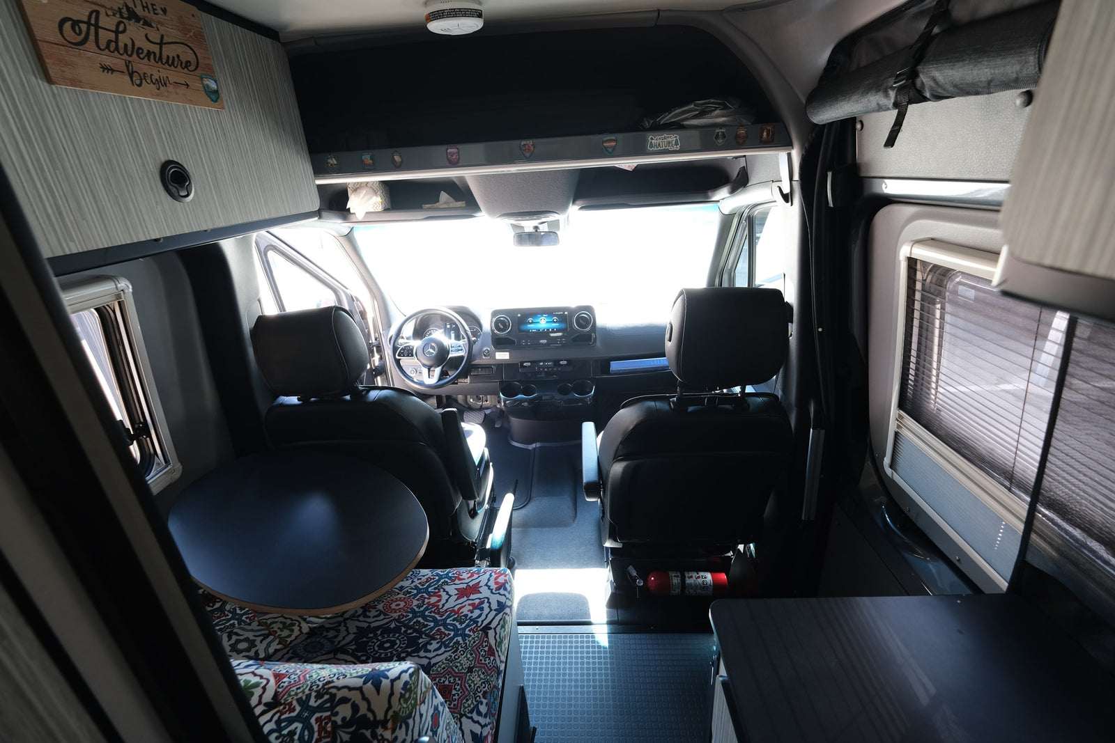 perfect for outdoor adventures.|Grey Mercedes Sprinter camper van rv rental parked on a sunlit forest trail among tall pine trees