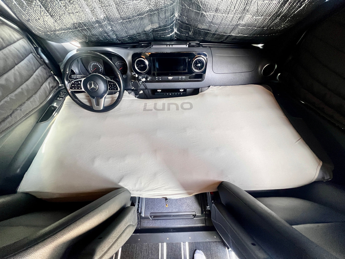 Cozy cab bed in an RV rental, featuring a Luno mattress for comfortable van camping in a Mercedes Sprinter.