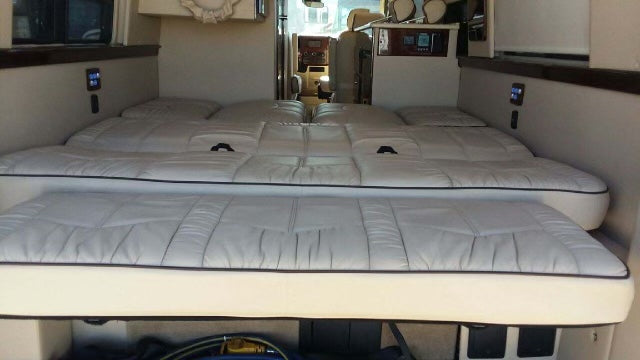 This RV rental offers comfortable, versatile two-tier white upholstered beds/seating, with controls visible for travel.