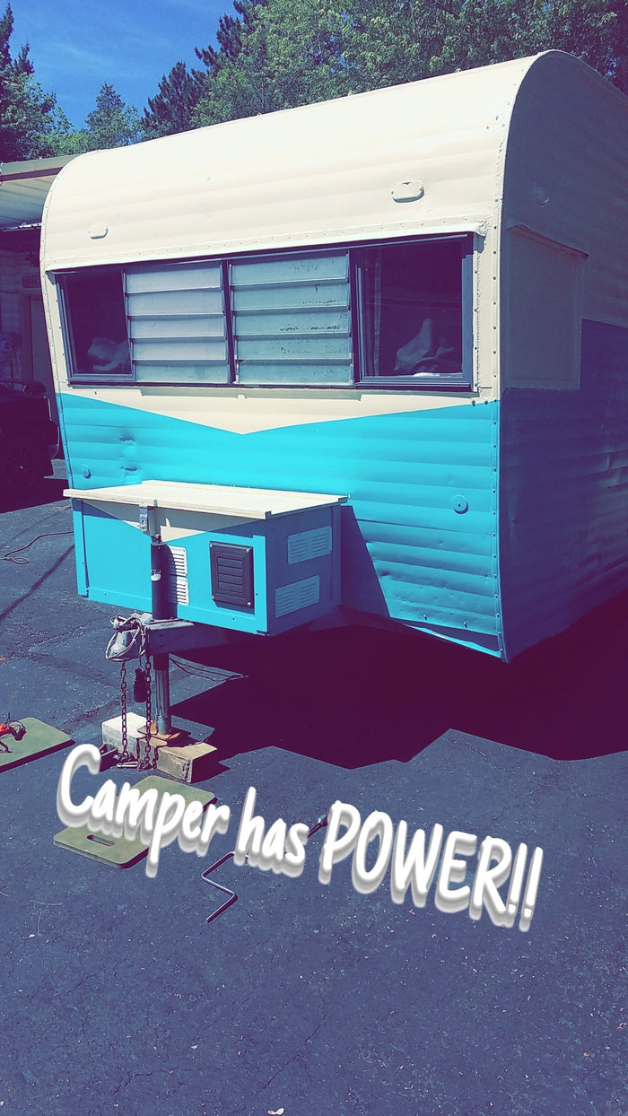 Vintage camper/RV rental now powered up! This two-tone unit, supported on jacks, is ready for adventures.