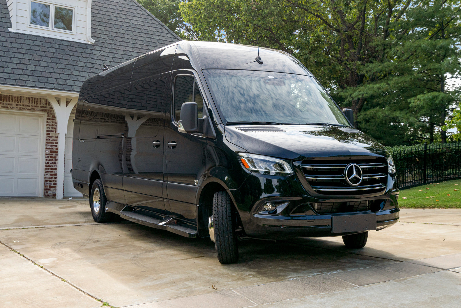Black Mercedes-Benz Sprinter conversion van, ideal for RV rental adventures, parked at a residence.