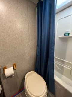 Experience RV rental comfort: a compact bathroom featuring a white toilet and blue shower curtain.