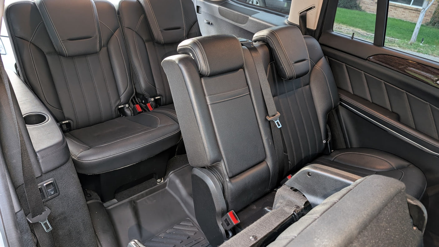 Black leather third-row seating in a spacious vehicle, ideal for an rv rental. Includes seatbelts, cup holders, and ISOFIX.