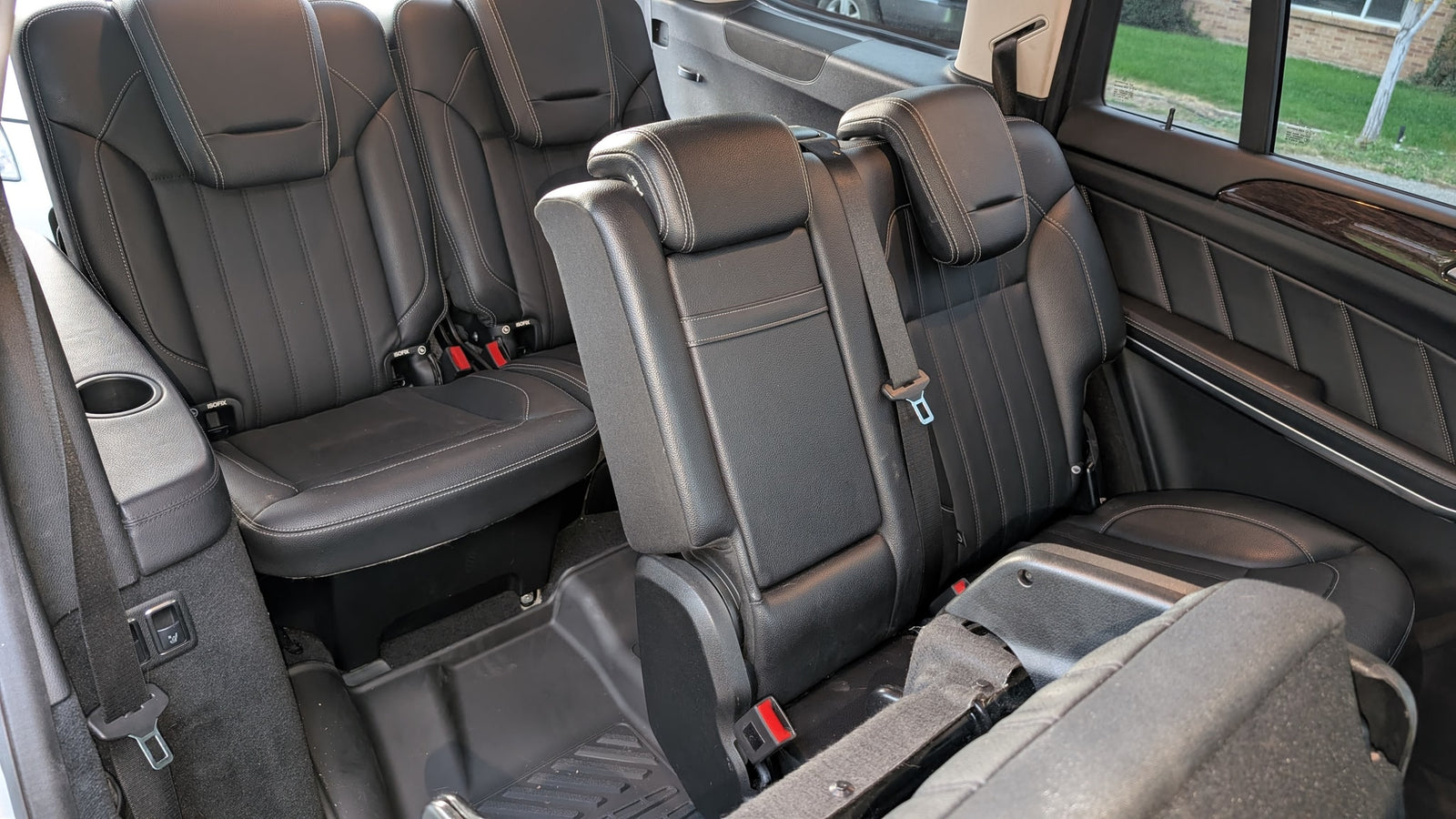Black leather third-row seating in a spacious vehicle, ideal for an rv rental. Includes seatbelts, cup holders, and ISOFIX.
