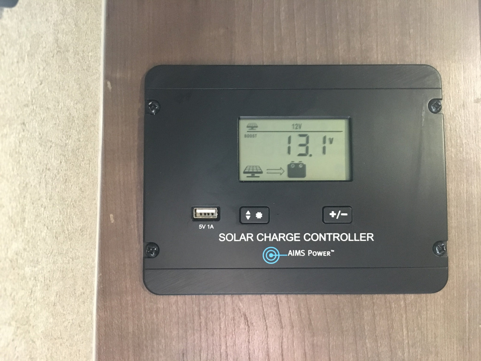 AIMS Power solar charge controller in an RV rental, displaying 13.1V battery voltage & 12V system. USB output for charging.