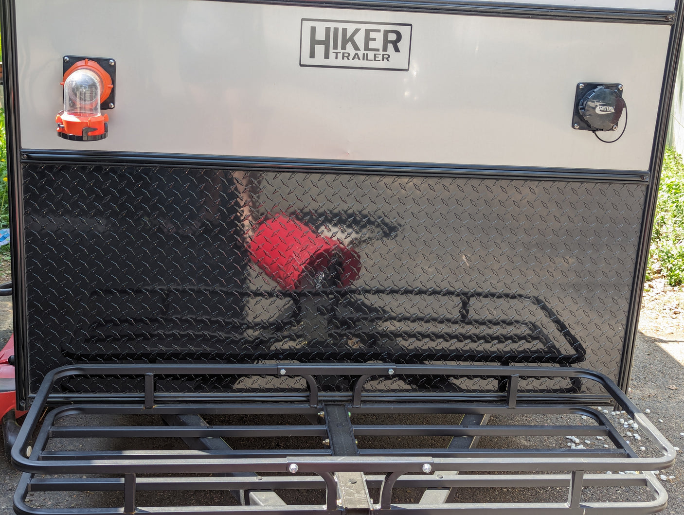Back of a Hiker Trailer RV rental, featuring utility hookups, durable diamond plate, and a rear cargo rack.
