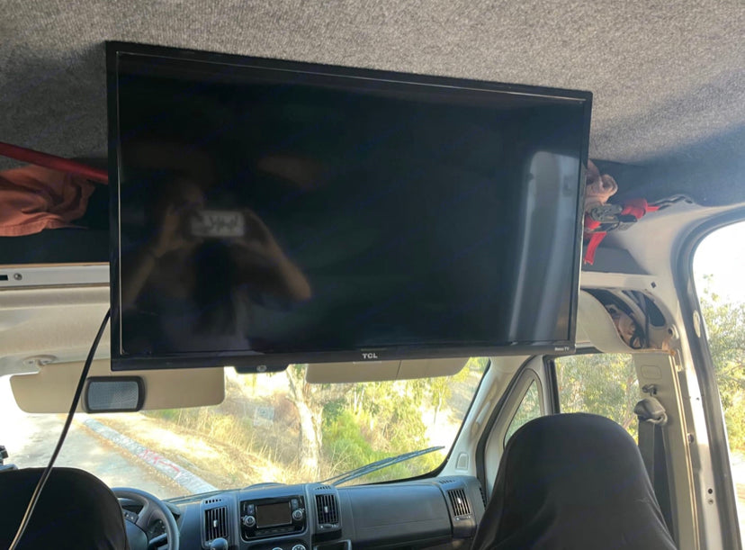 Interior of an RV rental camper van with a large TV mounted above the dashboard. Ideal for mobile entertainment.