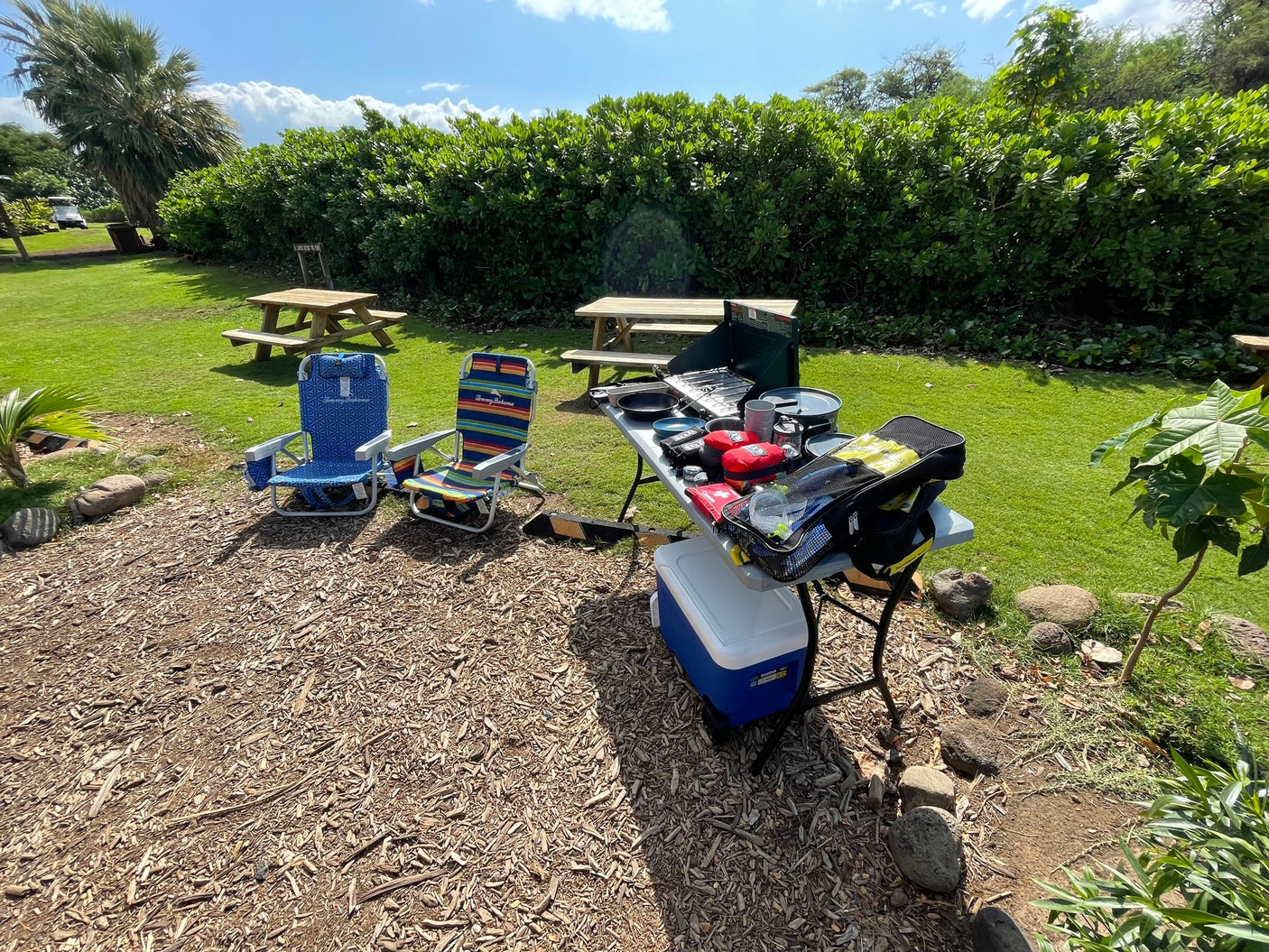 RV rental day! Outdoor kitchen setup with stove, cooler, chairs, & snorkel gear on wood chips for outdoor fun.