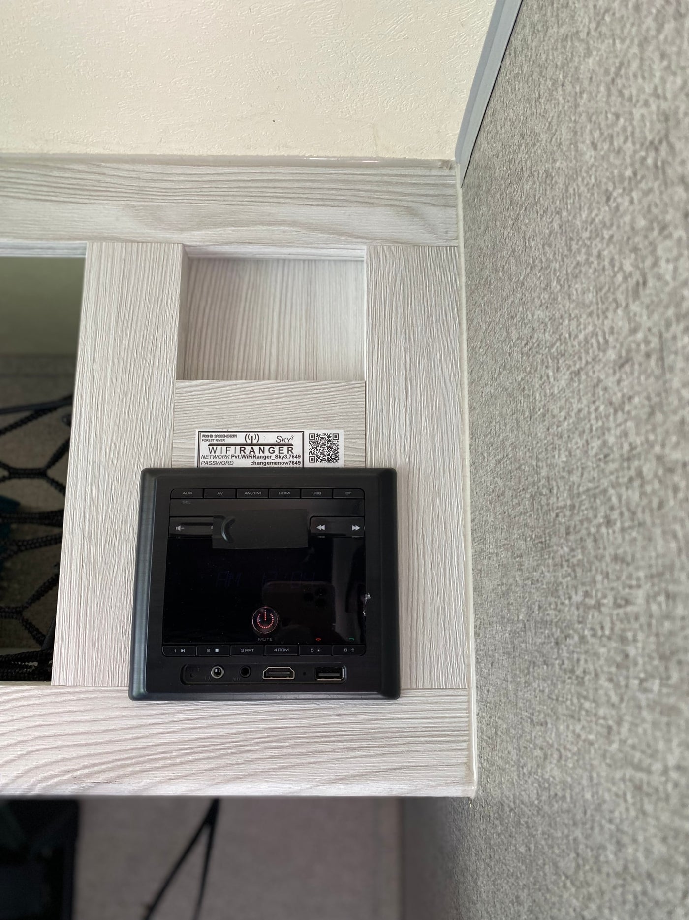 Inside an RV rental: a black entertainment control panel, with Wi-Fi network and password visible on a label above it. — photo 14